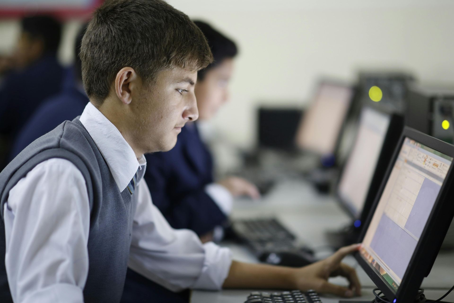 Student working on a computer in a classroom setting, focused on the screen displaying a spreadsheet application.