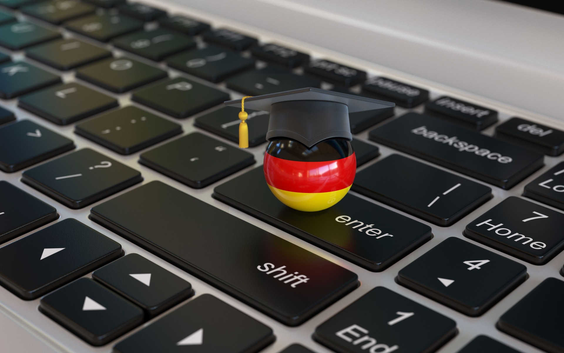 Deutsche Flagge mit Graduierungskappe auf Laptop-Tastatur