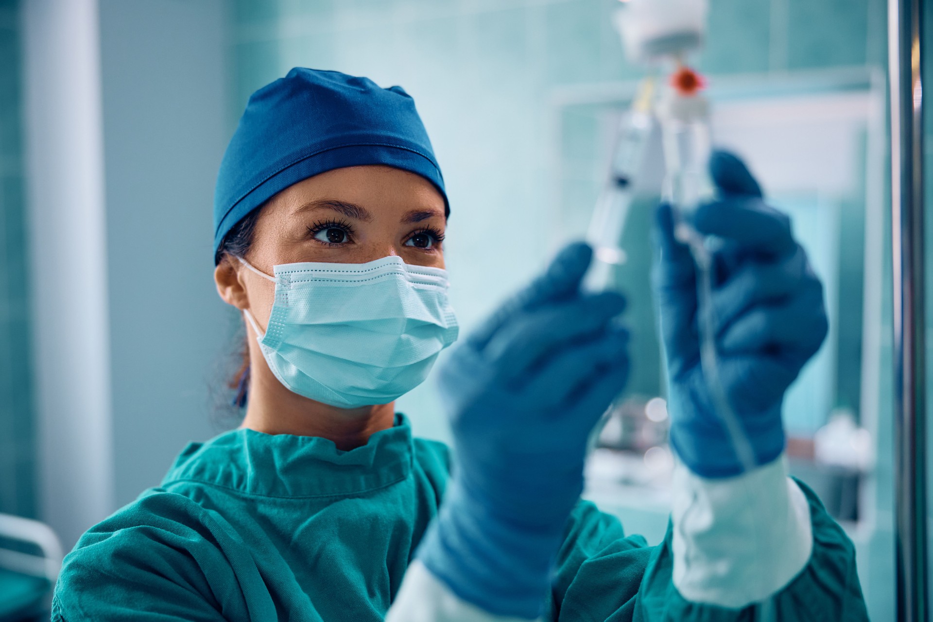 OP-Schwester injiziert Medikamente durch Infusionstropf im Operationssaal.