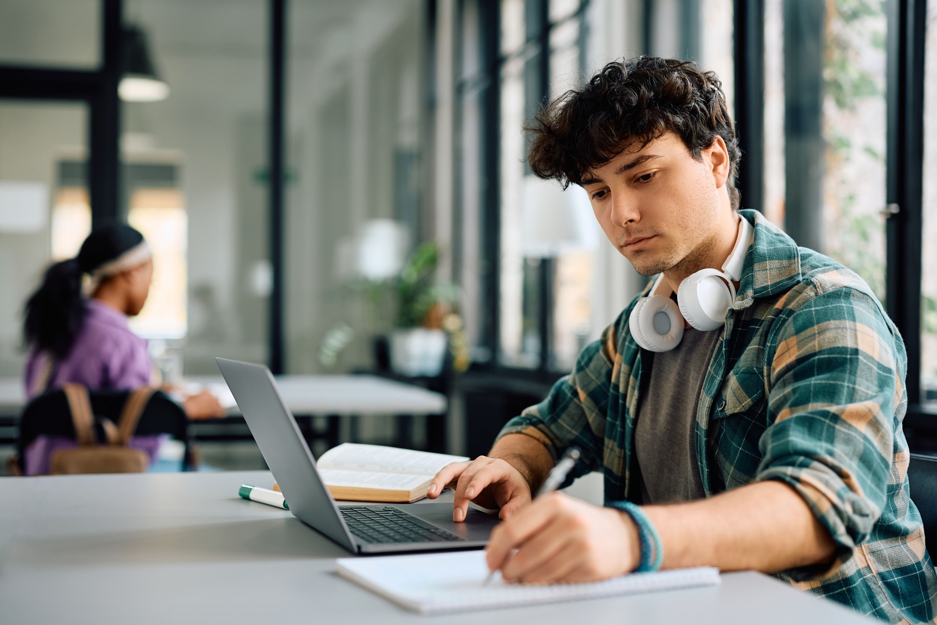 Junge Studentin macht sich Notizen während des E-Learnings auf dem Laptop an der Universität.